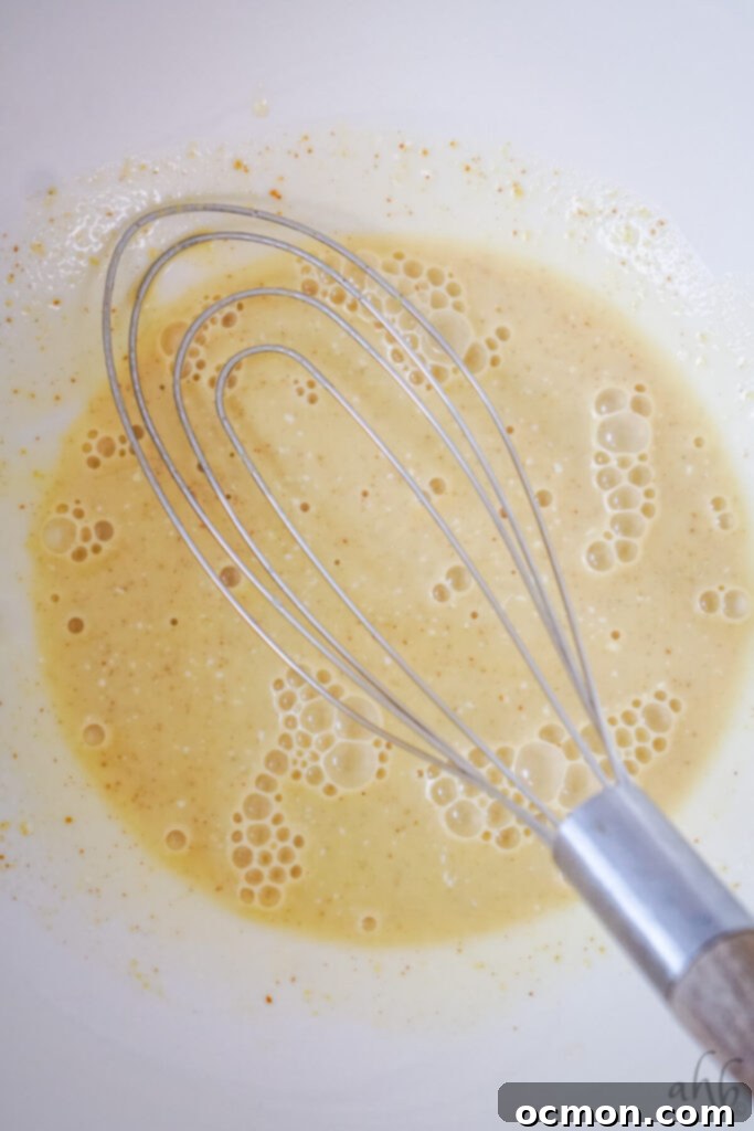 The dressing ingredients are whisked together in a white bowl.