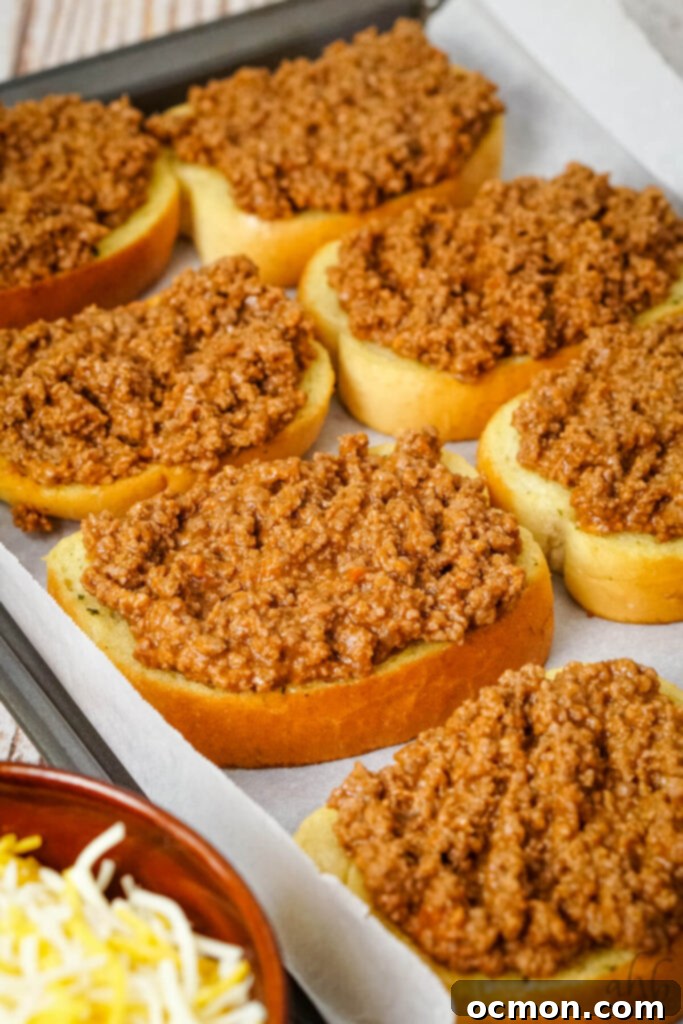 Sloppy Joe Stuffed Garlic Bread 7 A baking tray filled with freshly baked garlic bread slices, each generously heaped with the prepared sloppy joe ground beef mixture.