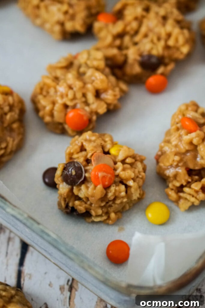 A pan of rice krispies no bake cookies with several reeces pieces laying nearby. 