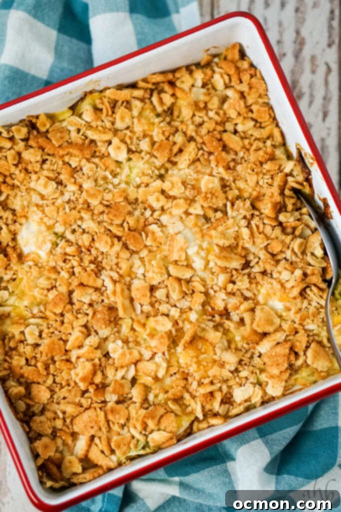 Effortless Creamy Cabbage Bake 7 A baked Scalloped Cabbage Casserole, perfectly golden brown and bubbling at the edges, is being scooped out of the pan with a serving spoon.