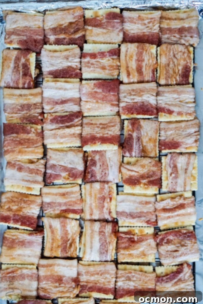 Cajun Caramelized Bacon Cracker Crunch 6 A tray full of uncooked Cajun Bacon Crackers, each cracker meticulously wrapped with a piece of seasoned bacon.