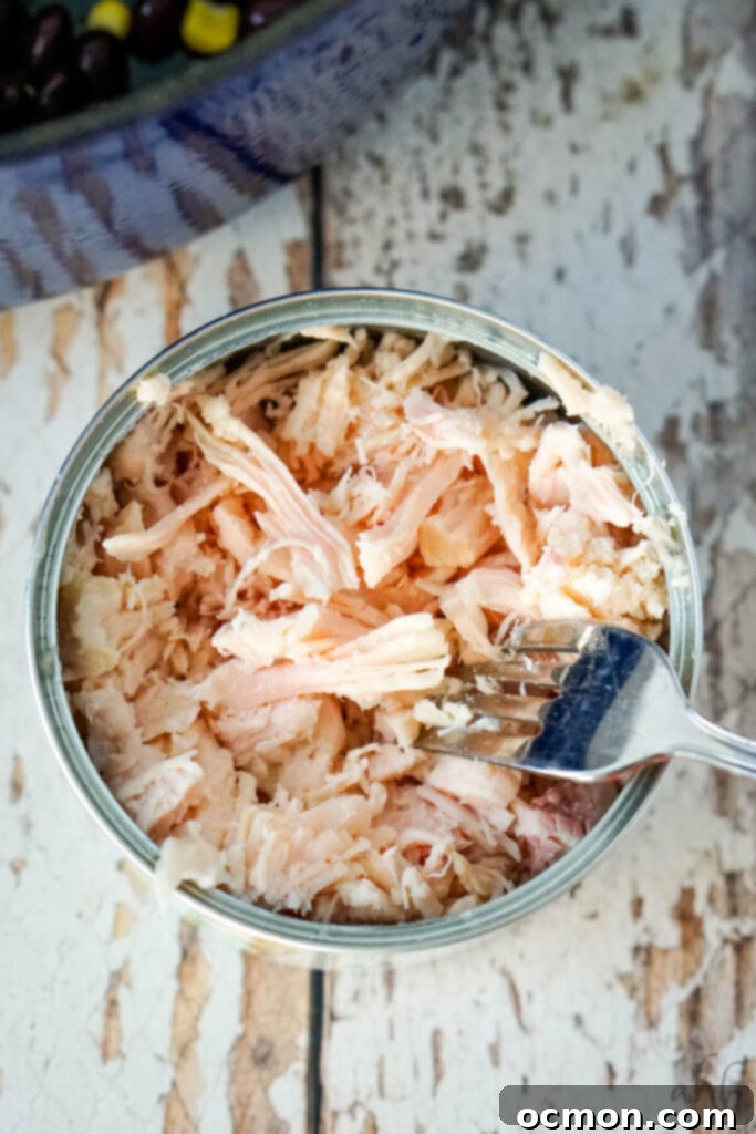 A can of Chunked chicken breast that has been shredded with a fork. 