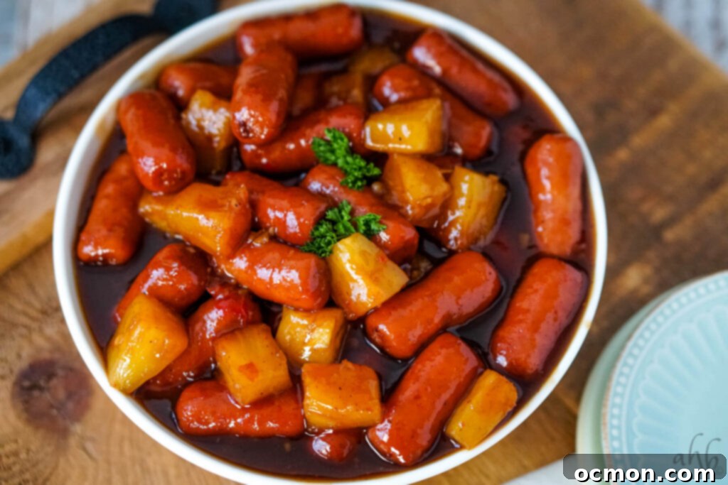 Aloha Smokies 3 A beautifully presented bowl of Hawaiian Lit'l Smokies with pineapple and glistening sauce on a rustic serving tray, ready for a party.