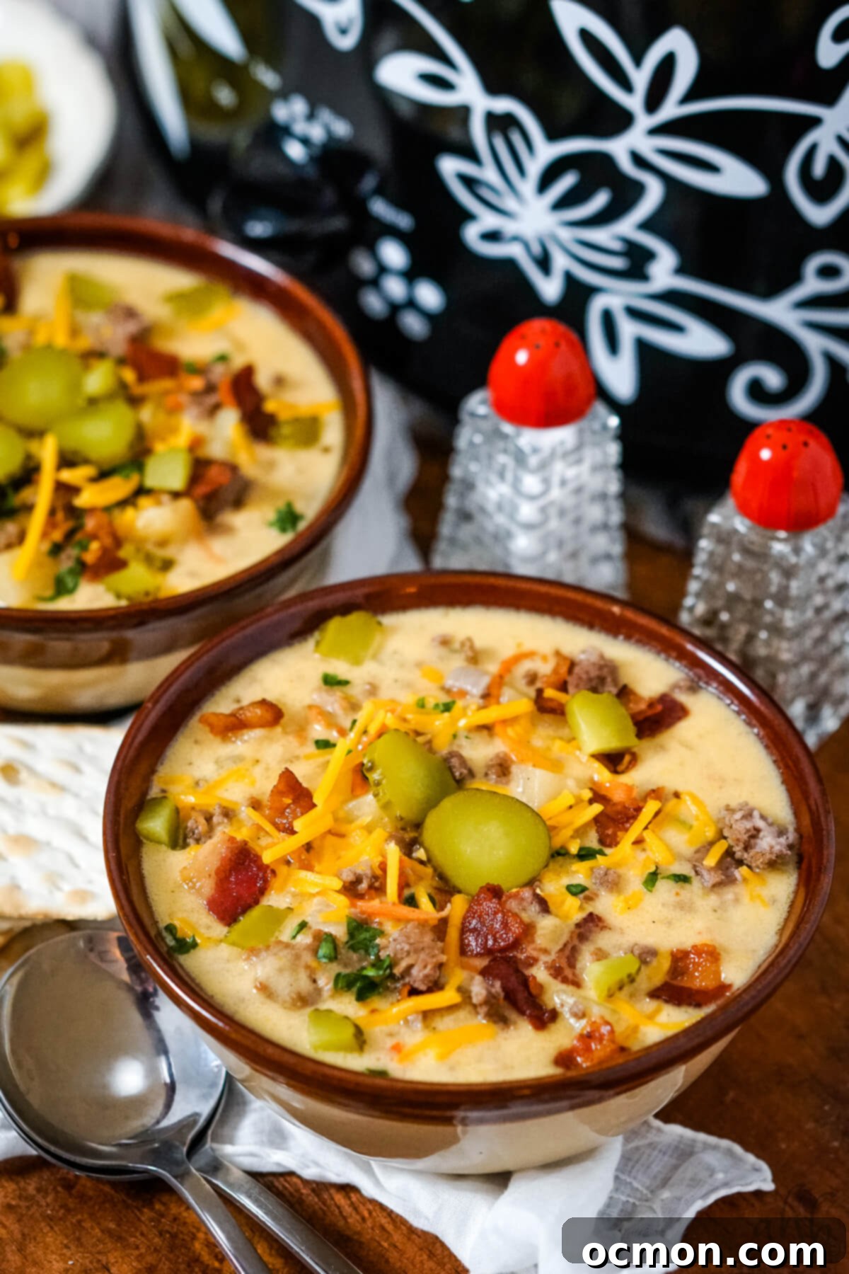 Creamy Slow Cooker Bacon Cheeseburger Soup 3 Two steaming bowls of slow cooker bacon cheeseburger soup ready to be served, sitting on a wooden tray beside the slow cooker itself, emphasizing convenience and deliciousness.