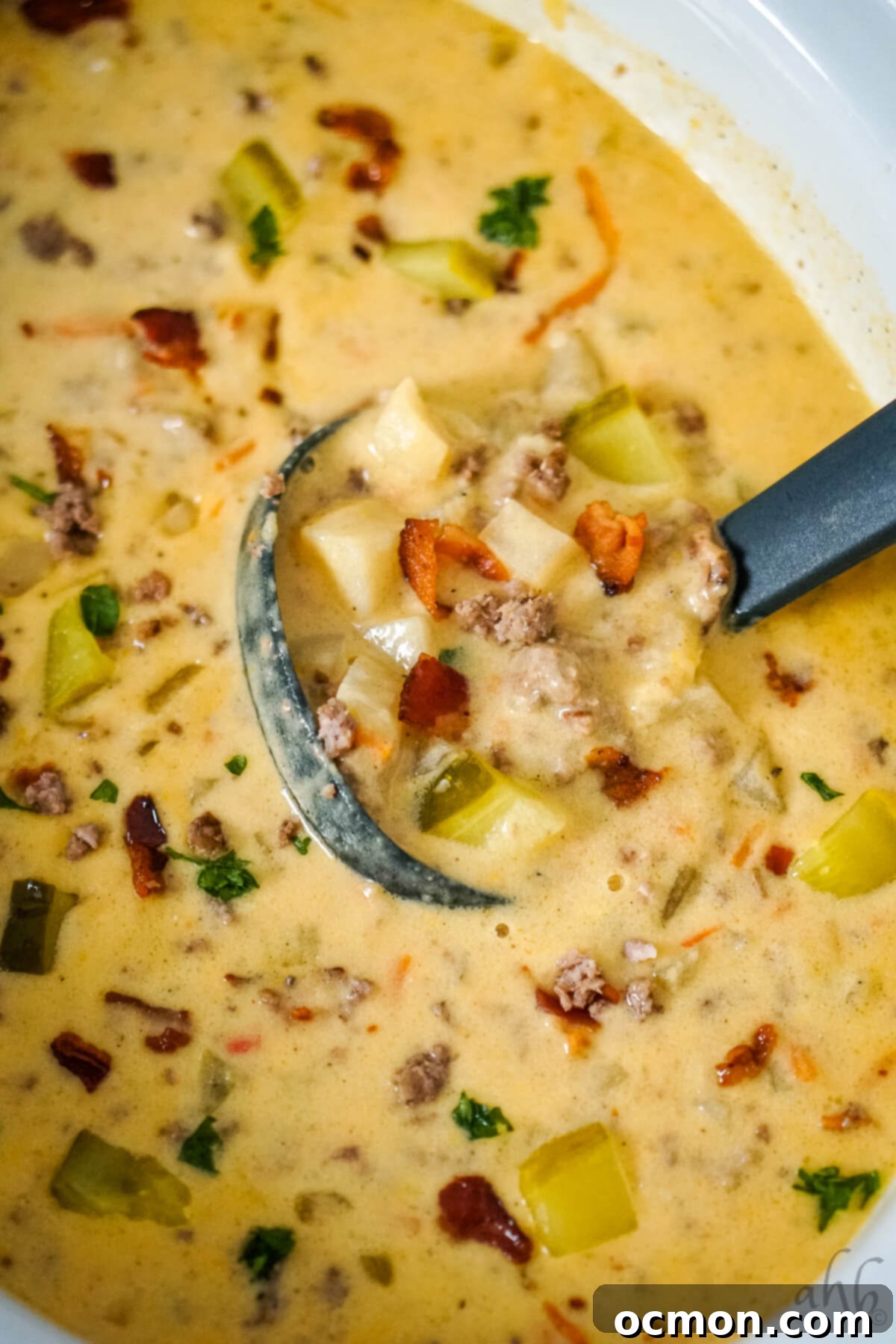 Creamy Slow Cooker Bacon Cheeseburger Soup 4 A ladle stirring the rich, creamy Slow Cooker Bacon Cheeseburger Soup directly in the slow cooker, showcasing the blend of ingredients.