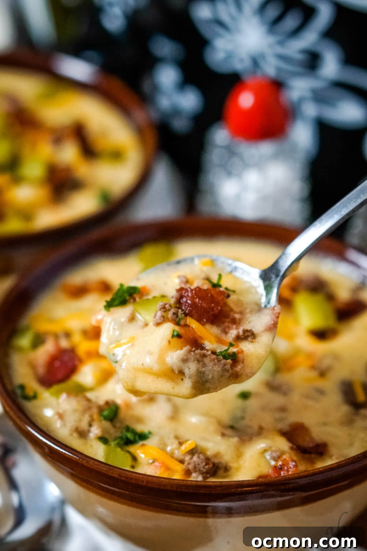 Creamy Slow Cooker Bacon Cheeseburger Soup 5 A close-up image of a spoon lifting a generous portion of slow cooker bacon cheeseburger soup, showcasing the creamy texture and rich ingredients like ground beef and potatoes.