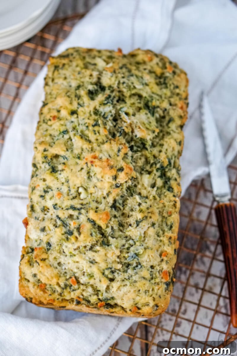 A perfectly baked loaf of spinach and feta beer bread cooling on a wire rack, showing its golden crust and delicious texture.