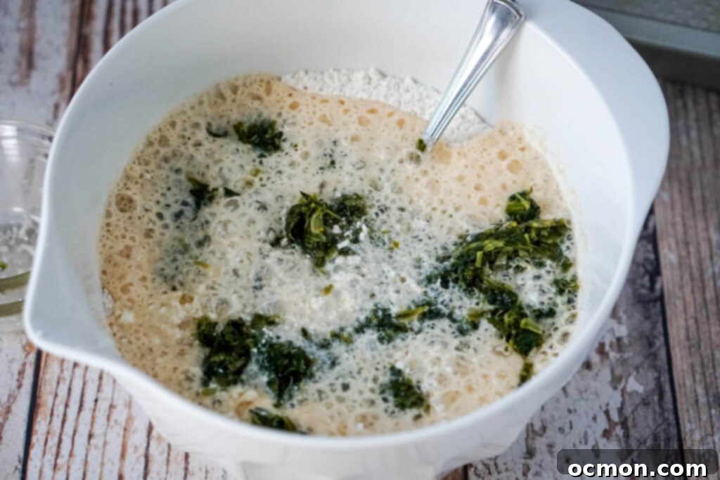 Adding beer, feta cheese, and squeezed spinach to the dry ingredients in a mixing bowl.