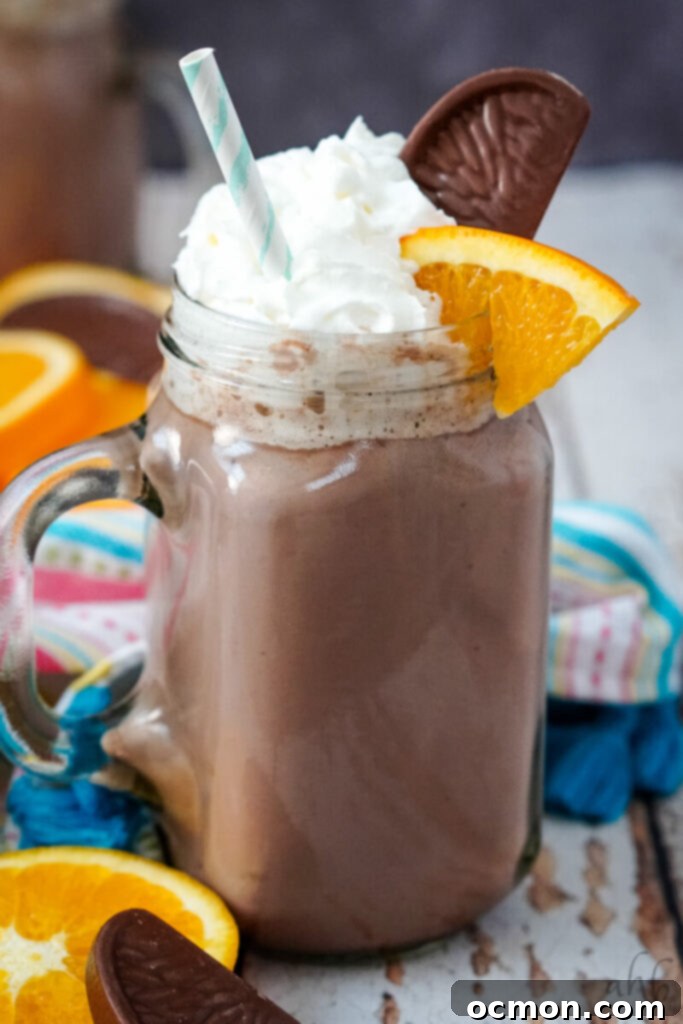 A close up image of a mug of orange hot chocolate with a colorful striped napkin in the background. 
