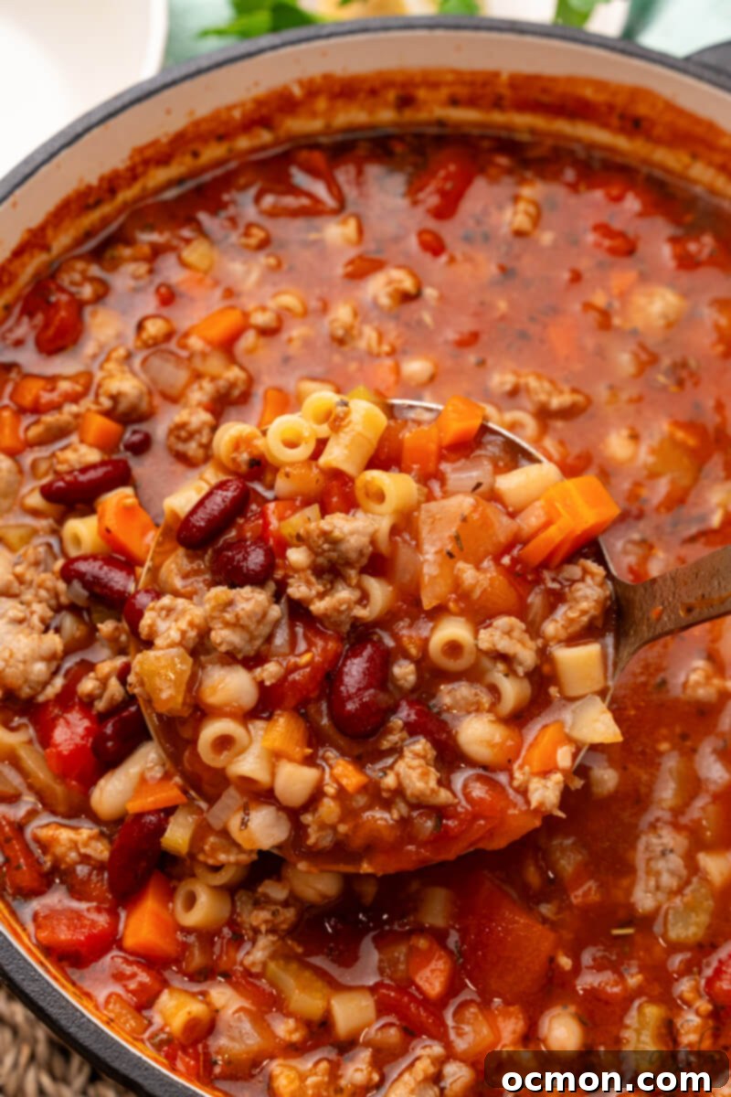 Effortless Sausage Pasta Fagioli 3 A ladle holds a scoop of Pasta Fagioli over the pot.