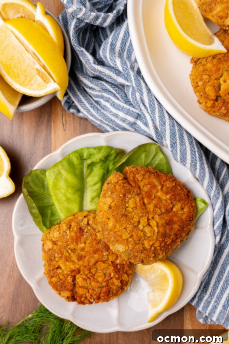 Grandma's Classic Salmon Patties 4 A white plate with two salmon patties and a wedge of lemon to one side.