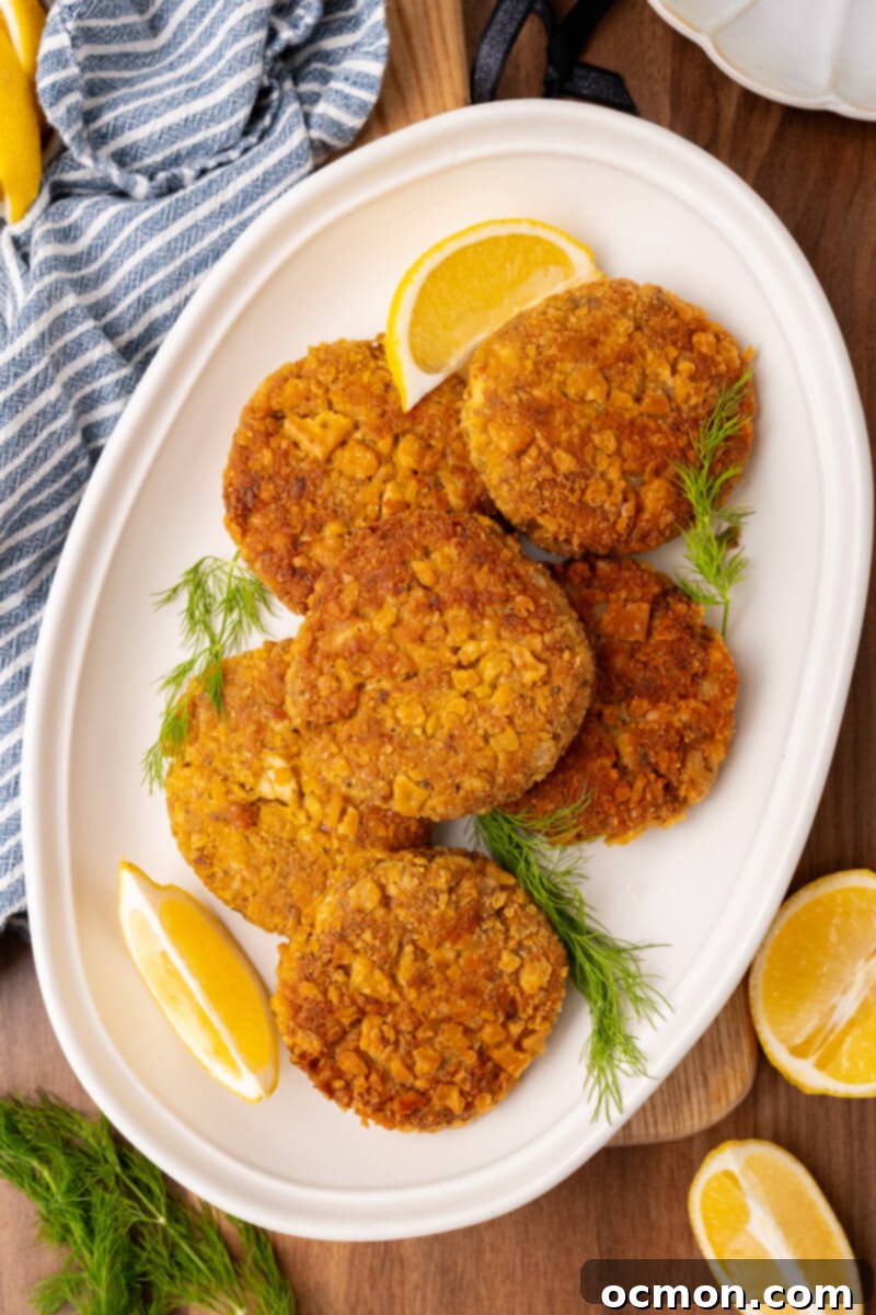 Grandma's Classic Salmon Patties 10 A white plate of salmon patties served with slices of lemon and garnished with dill weed.