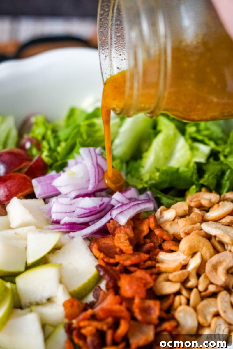 Zesty Cashew Crunch 9 The freshly prepared curried vinaigrette dressing is being poured generously over the assembled Cashew Nut Salad, ready for tossing.