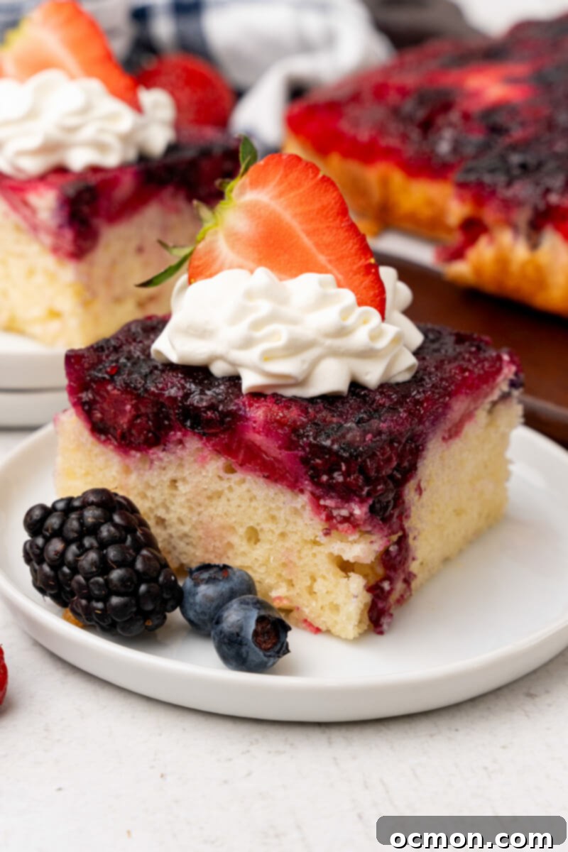 A piece of Berry Upside Down cake on a white plate with whipped cream