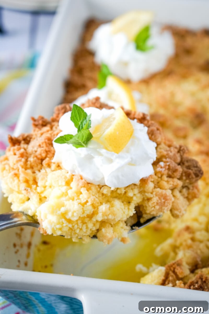 Bright Lemon Dump Cake 3 A perfectly portioned scoop of lemon dump cake, complete with toppings and garnish, is being lifted from the baking pan, showcasing its luscious layers.