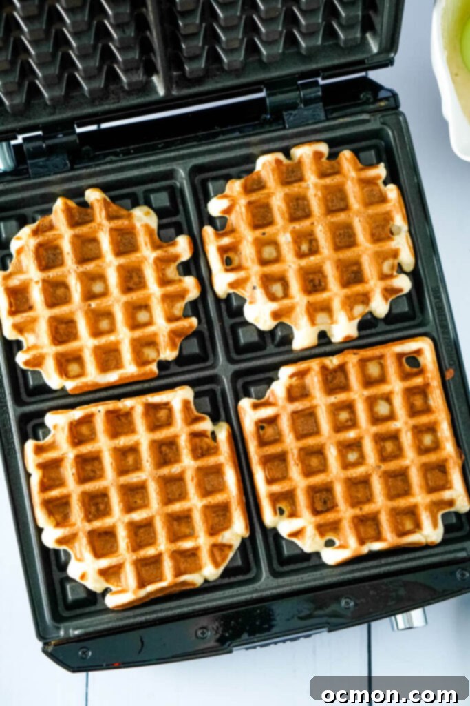 Crispy and golden waffles sit finished on the waffle maker.
