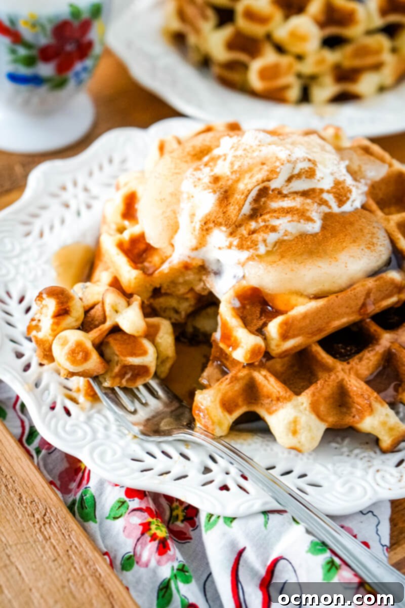A bite has been taken out of the stack of waffles and sits on the fork.