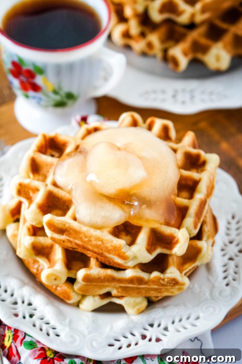 A stack of two waffles are topped with apple pie filling.