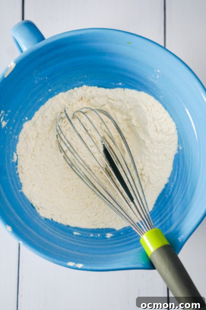 The dry ingredients are mixed with a whisk in a blue bowl.