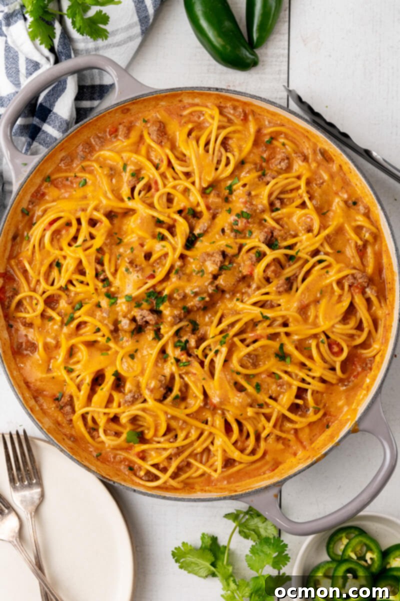 A skillet full of irresistible cheesy taco spaghetti, freshly topped with vibrant chopped cilantro, presented as a finished dish.