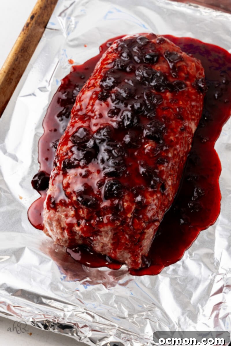 A thick layer of rich bourbon glaze is poured over the raw meatloaf, promising a delicious caramelization during baking.