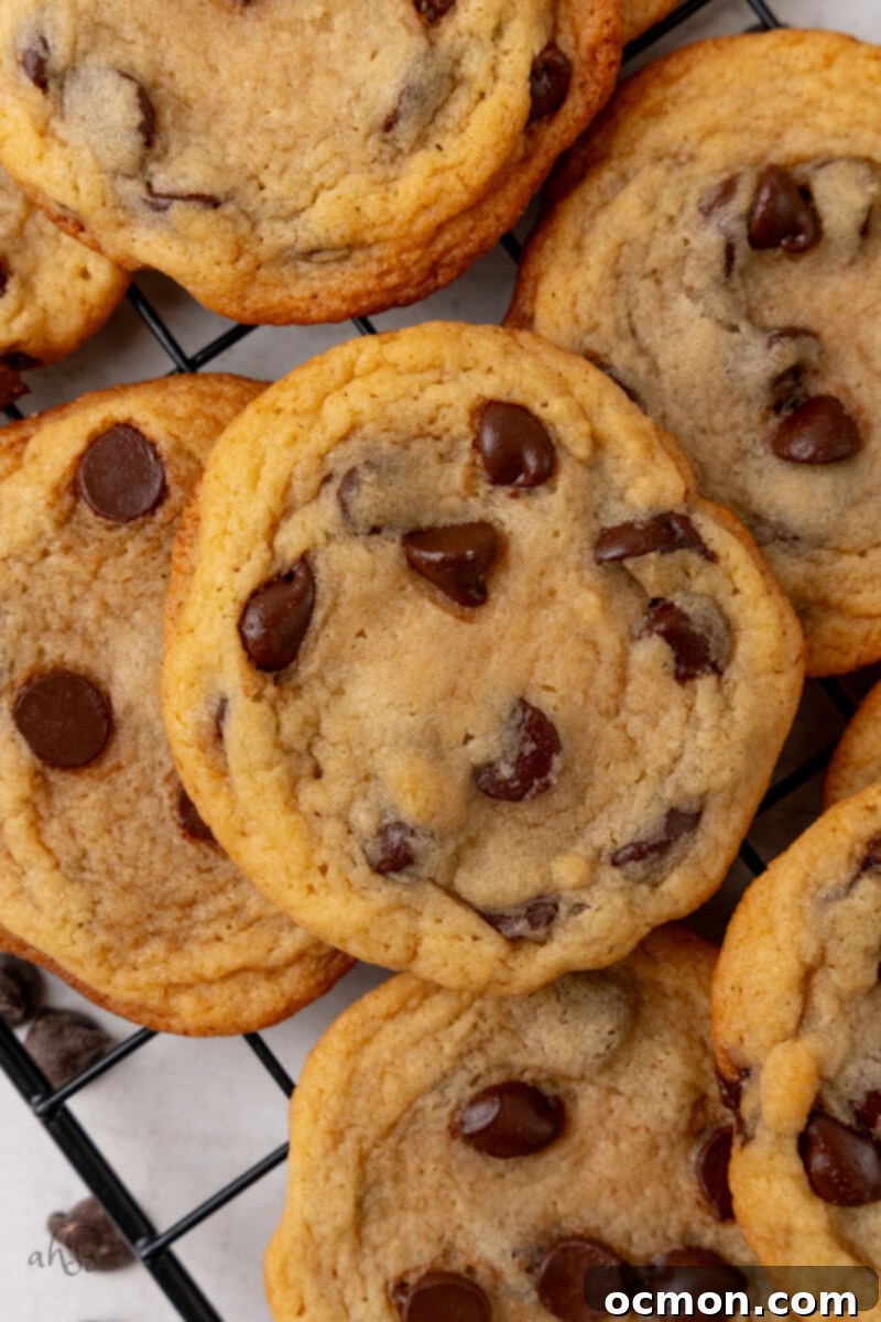 A pile of freshly baked Malted Chocolate Chip Cookies cooling on a wire rack, ready to be enjoyed.