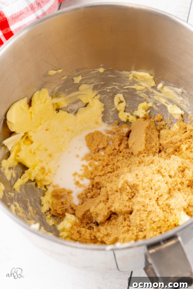 The wet ingredients – softened butter, butter-flavored Crisco, and sugars – are being creamed together in a metal bowl, forming a light and fluffy mixture.