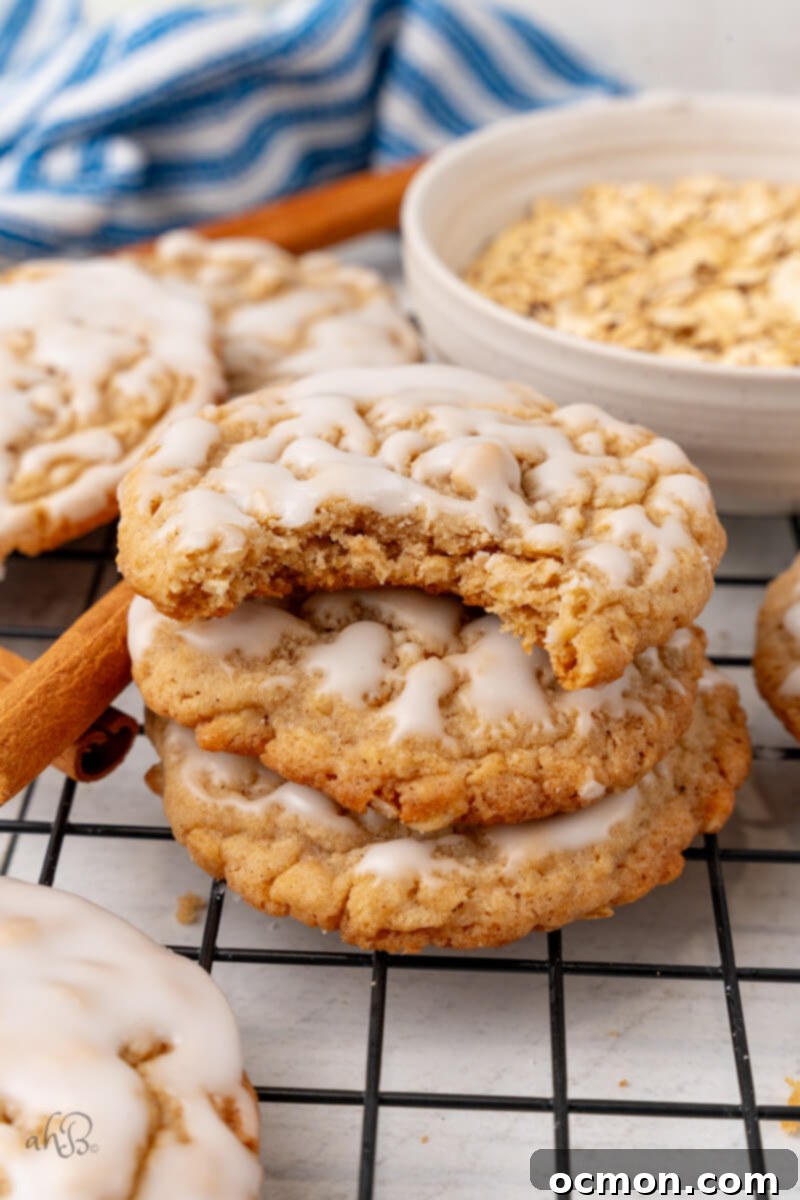 Iced Oatmeal Cookies-16 A stack of three soft iced oatmeal cookies, with the top cookie showing a delicious bite taken out, revealing its tender interior.