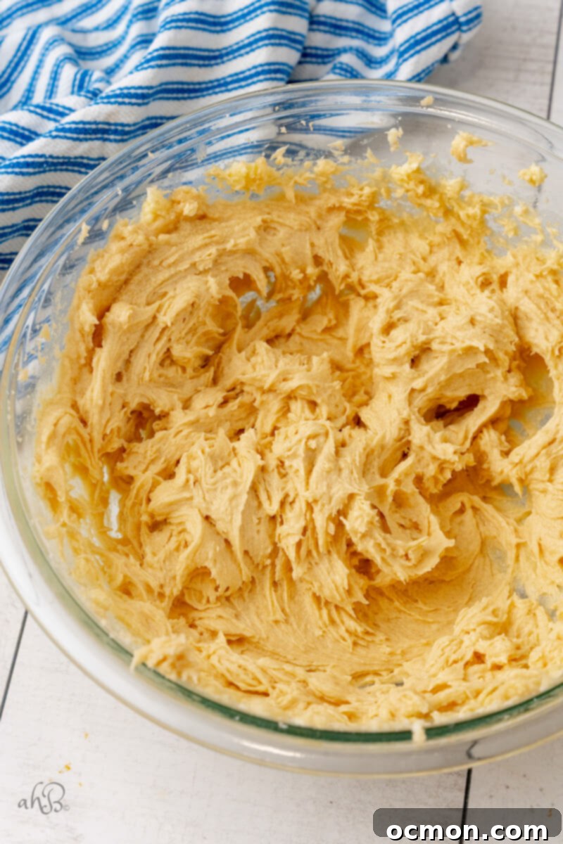 Iced Oatmeal Cookies-4 Butter, Crisco, and sugars are being creamed together in a mixing bowl using an electric mixer, creating a light and fluffy mixture.