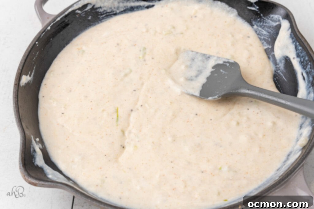 The sour cream has been stirred into the skillet with the spatula.