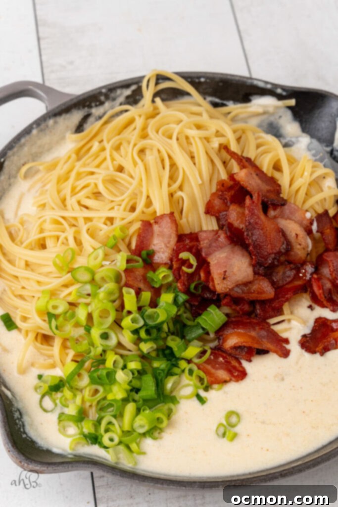 The pasta, bacon pieces, and green onions are added to the skillet.