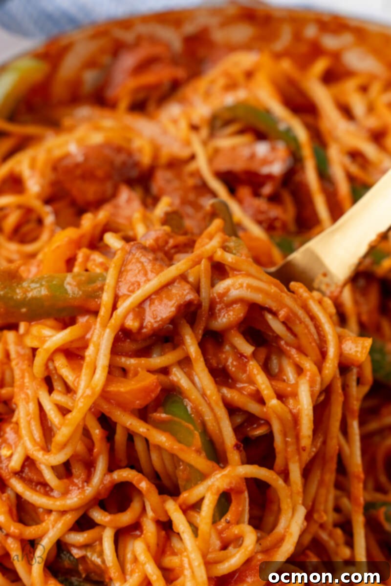 Cajun Sausage Spaghetti is stirred with a wooden spoon.