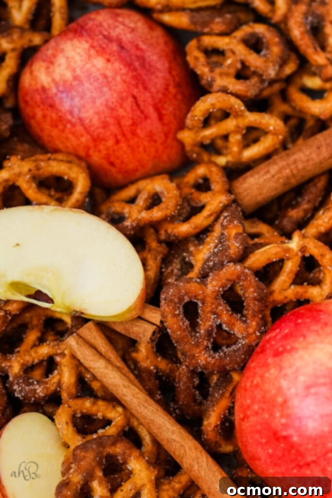 Spiced Apple Cider Pretzels 5 A generous pile of freshly made apple cider pretzels, artfully arranged with whole cinnamon sticks and slices of fresh apple, emphasizing the key flavors.