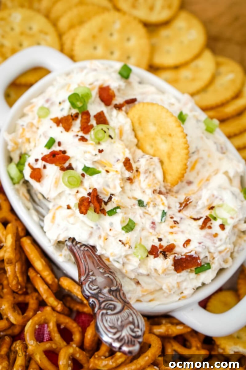 A cracker and spreading knife are sitting in the dish of Ranch Beer Cheese dip.