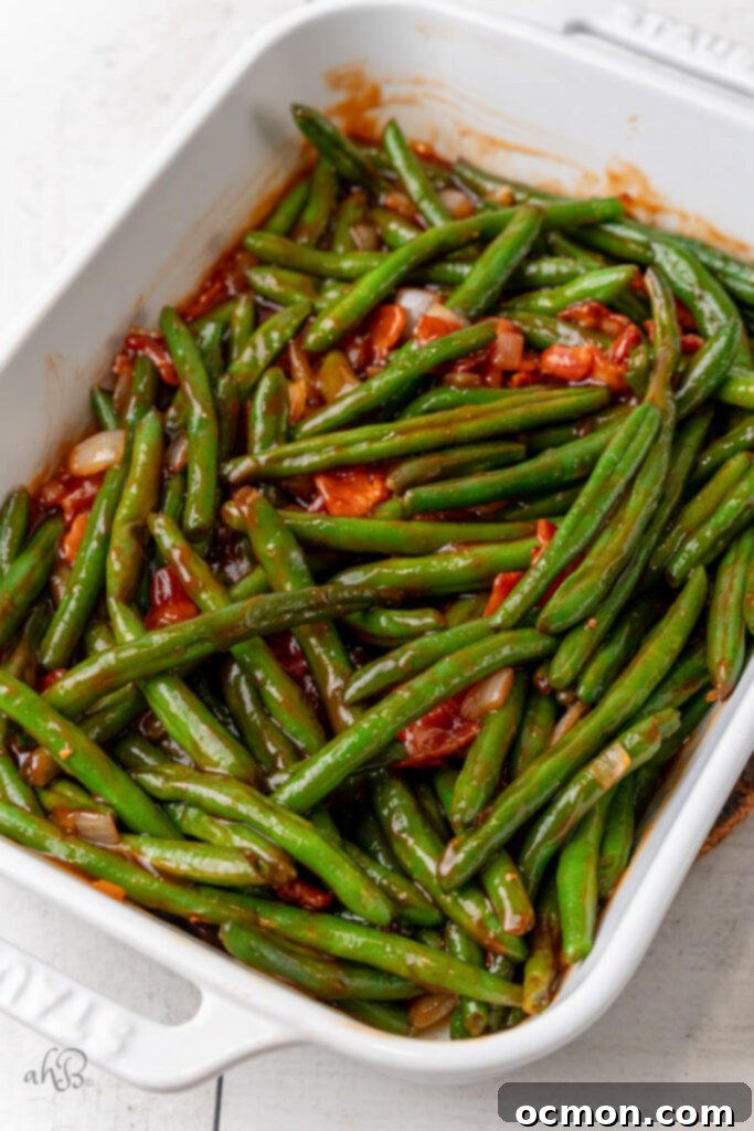 Green beans and cooked bacon pieces are added to the BBQ mixture in the skillet and stirred to coat.