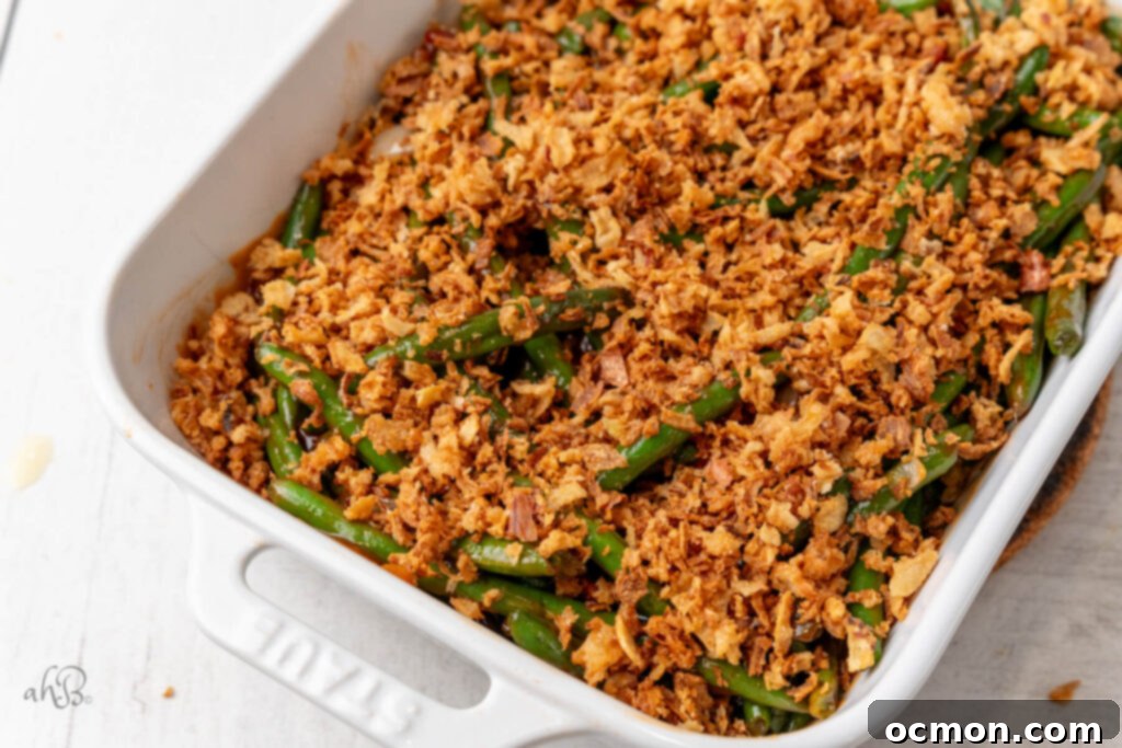 French fried onions are generously sprinkled on top of the green bean casserole in a baking dish before baking.