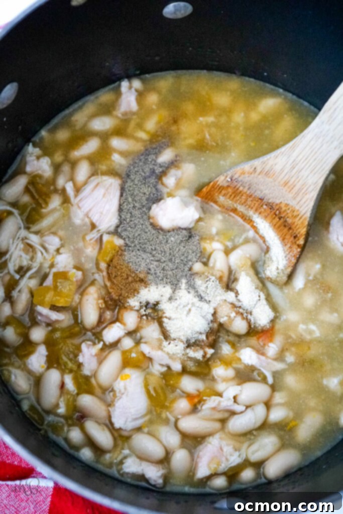 All the prepared ingredients for the 7-Can White Chicken Chili are combined in a large pot, which is then placed on the stovetop, ready to simmer and meld all the flavors together.