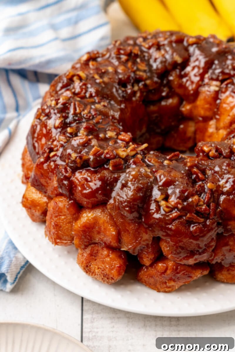 A close-up shot of the finished Bananas Foster Monkey Bread on a white serving plate, showing its rich, glossy topping.