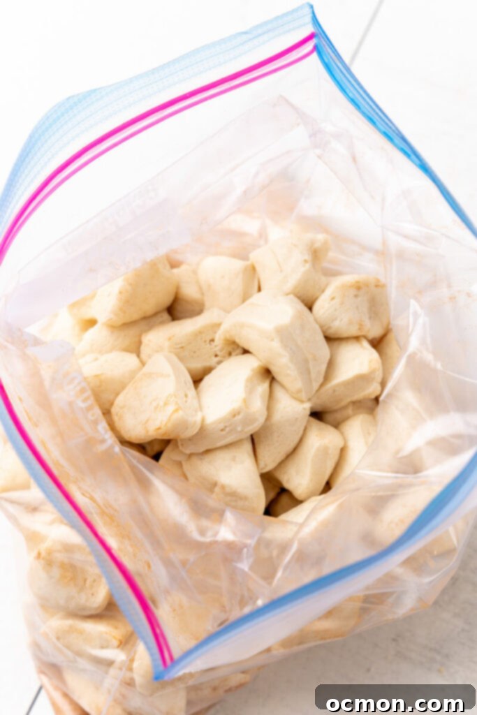 The cut biscuit pieces are placed inside an open gallon-sized Ziploc bag, ready for coating.