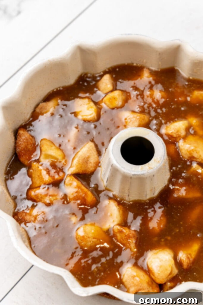 The Bananas Foster caramel sauce is poured evenly over the biscuit pieces in the Bundt pan.