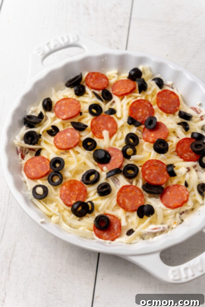 Spread the pepperoni dip into a pie plate, top the dip with the shredded mozzarella, reserved pepperoni slices, and black olives if using. Bake at 350 degrees for 25 minutes. Or if serving cold, serve immediately!