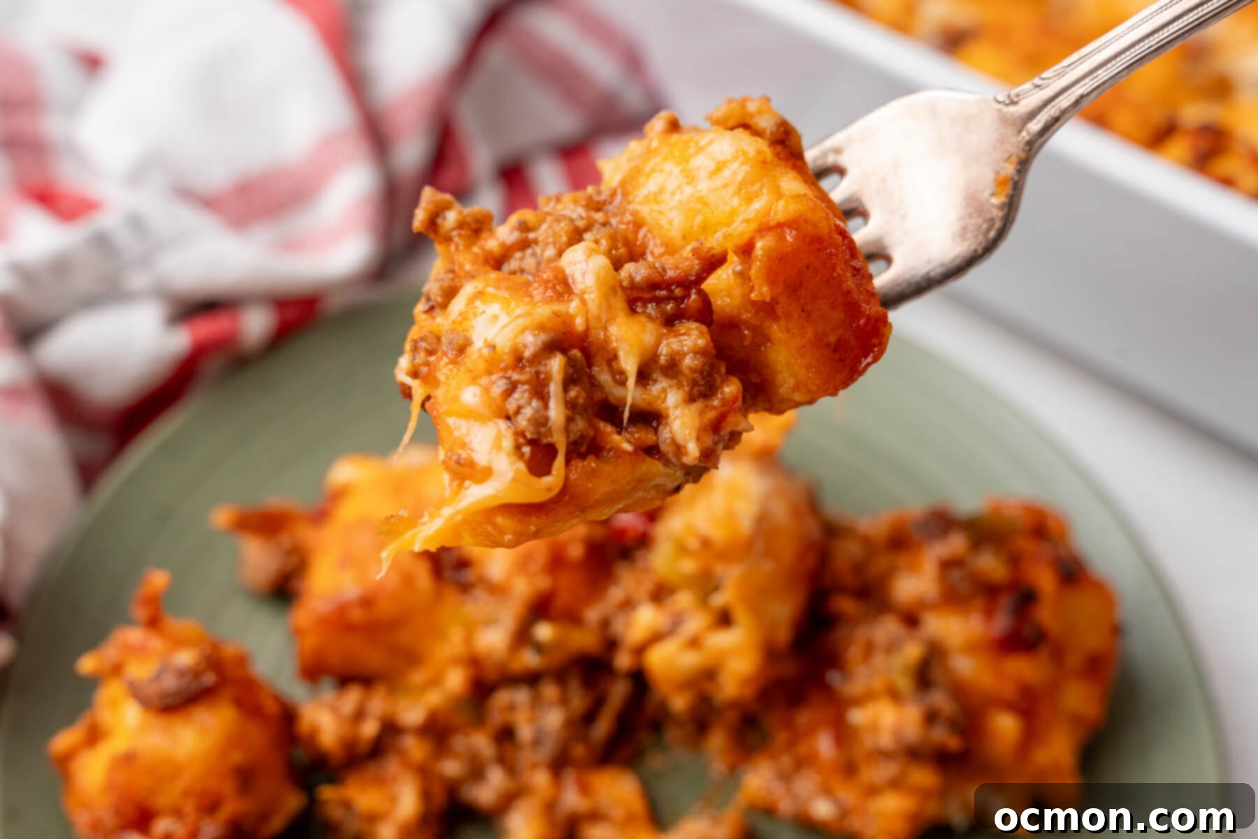 A fork lifting a delicious bite of cheesy Sloppy Joe Biscuit Casserole from a plate, showing the rich meat mixture and tender biscuit pieces, ready to be enjoyed.