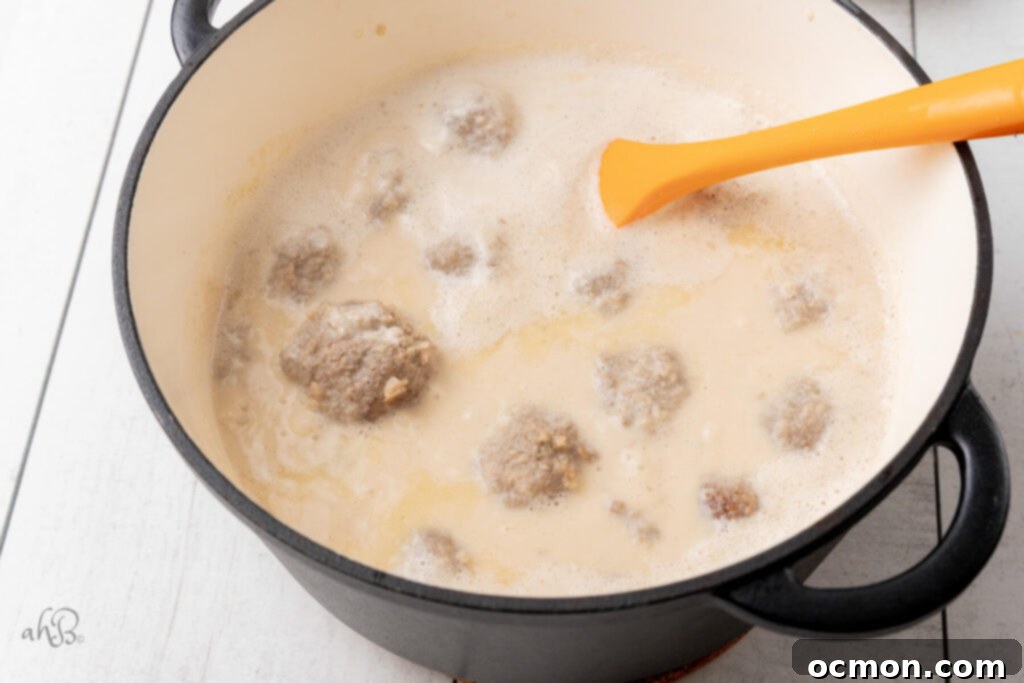 A Dutch oven filled with the Swedish meatballs, with the ingredients for the gravy being added.