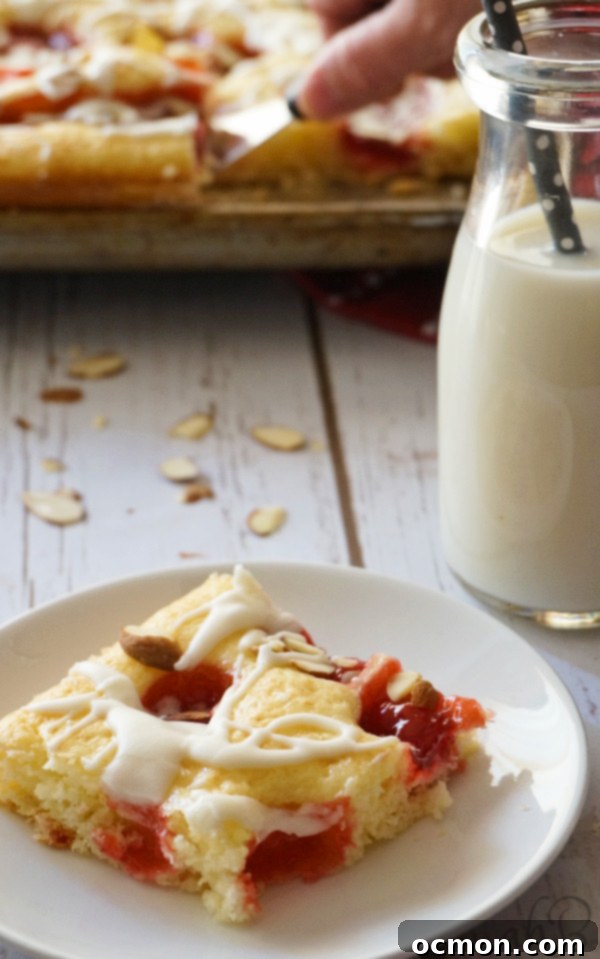 A freshly cut slice of Cherry Almond Square, showing the moist cake base, rich cherry layer, and the sweet almond glaze with sliced almonds.