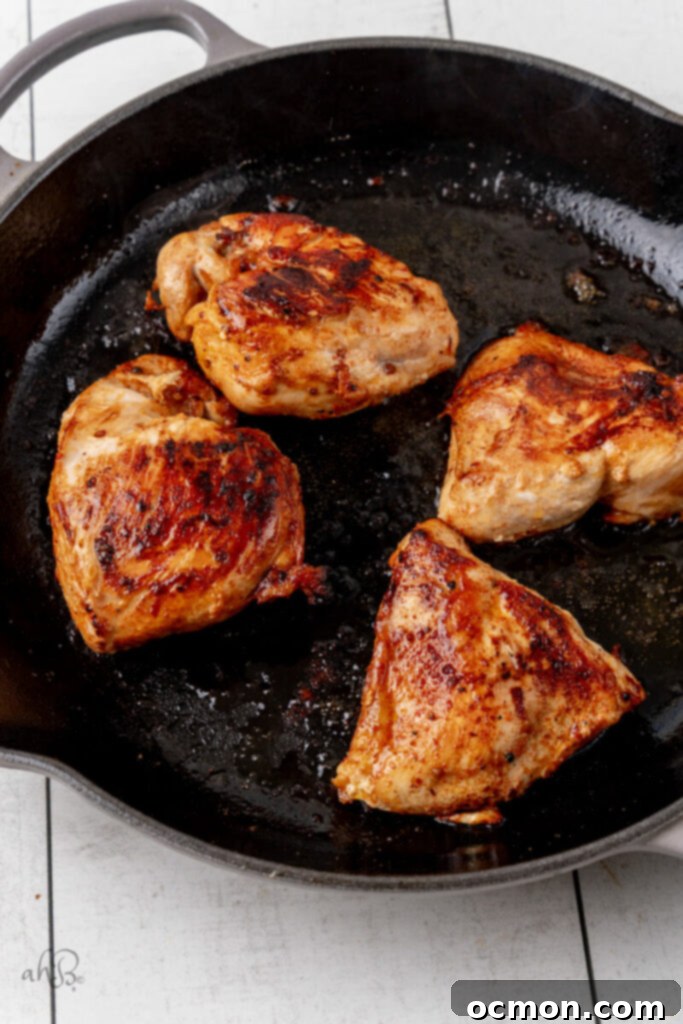 The cooked chicken is browned and cooked with oil in the skillet.