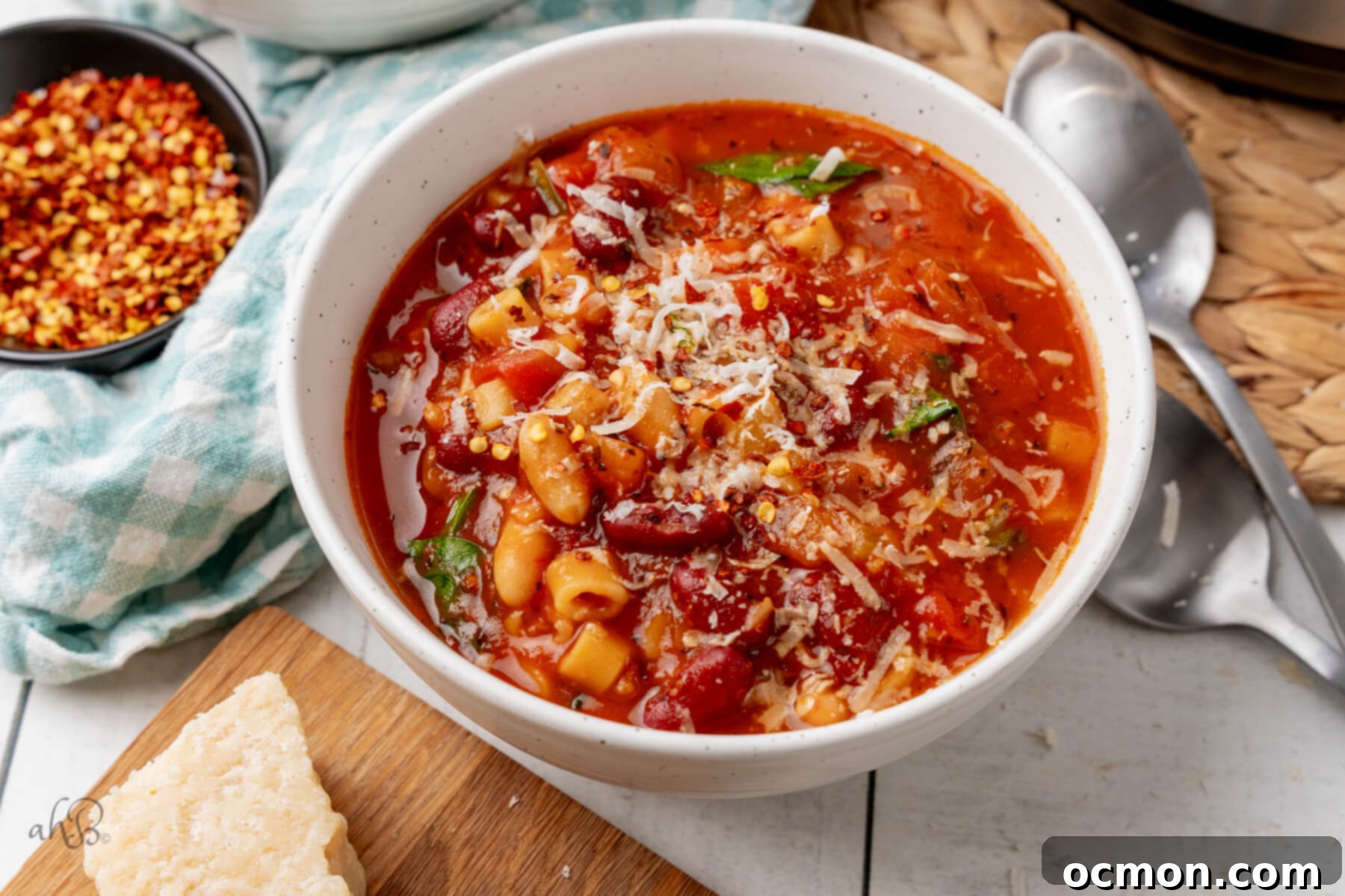 A steaming white bowl of homemade Instant Pot Minestrone Soup, garnished with fresh herbs and a sprinkle of Parmesan cheese.