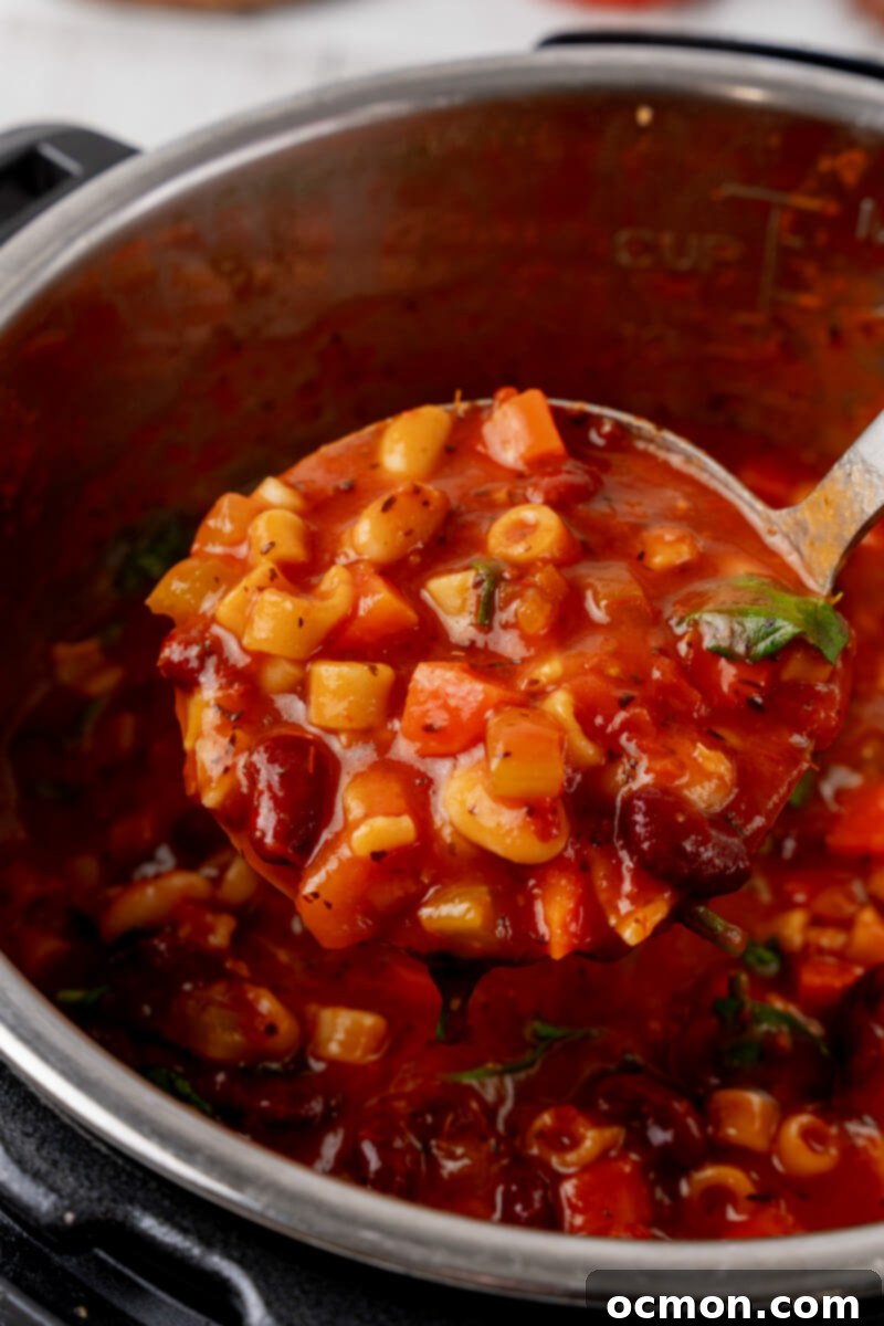 A ladle scooping rich Minestrone soup directly from the Instant Pot, showing pasta and vegetables.