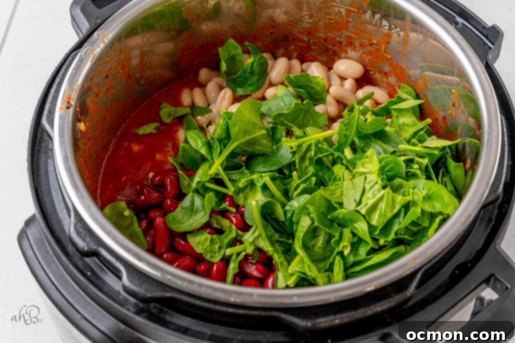 Rinsed kidney and cannellini beans, along with fresh spinach, are stirred into the cooked Minestrone soup in the Instant Pot.