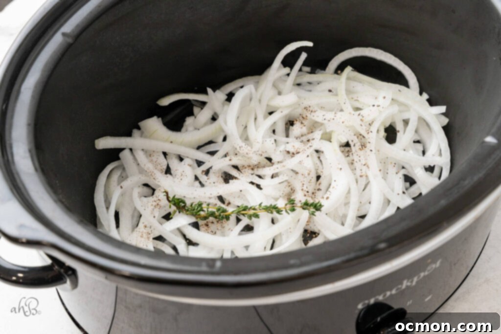 Easy Slow Cooker French Onion Chicken 5 The onions, thyme, and pepper, are added to the bottom of the crockpot.