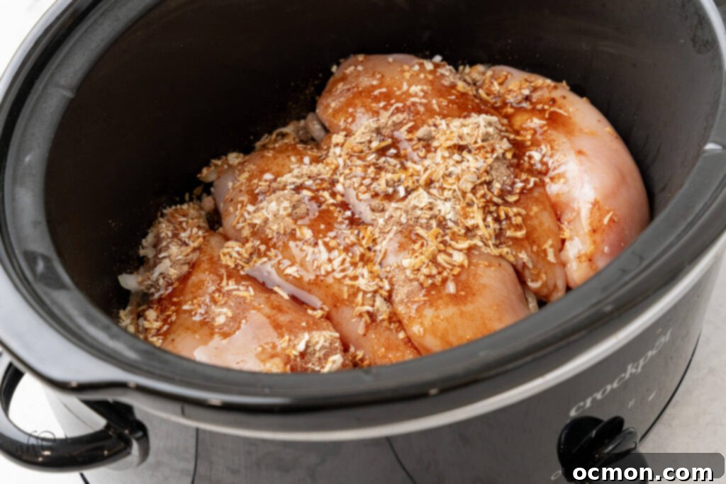 Easy Slow Cooker French Onion Chicken 6 Chicken, consommé, and onion soup mix are added to the crockpot.